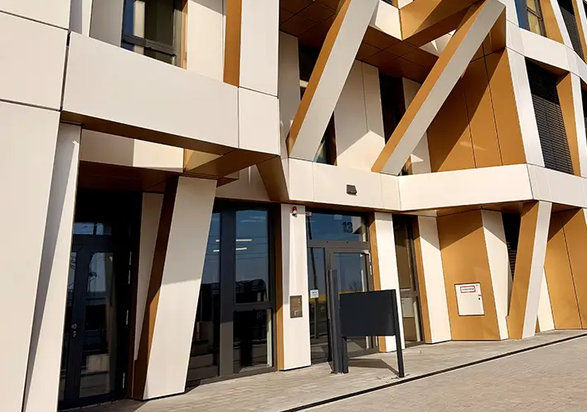 Detailed view of the entrance area of Brainfactory Bochum, featuring a distinctive façade structure, angled support elements, and modern architecture in white and gold tones.